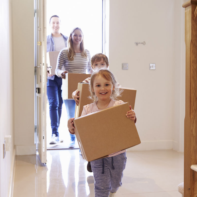 Photo of young family moving into their new house after getting their new mortagage with boxes in their arms