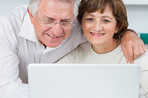 Couple looking at computer while they search for equity release information that is provided by Acclaimed Mortgage Consultancy